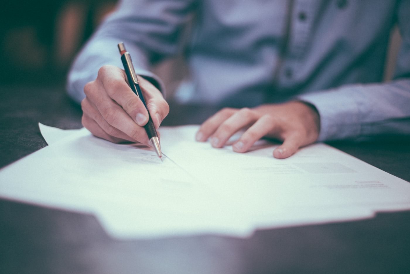Hands signing a document with a pen